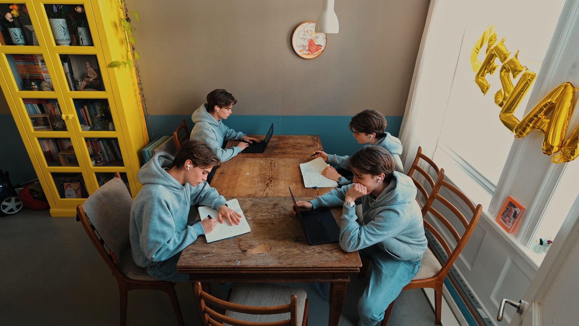 Jacob Schneider shown four times around one table, writing and working on two laptops.